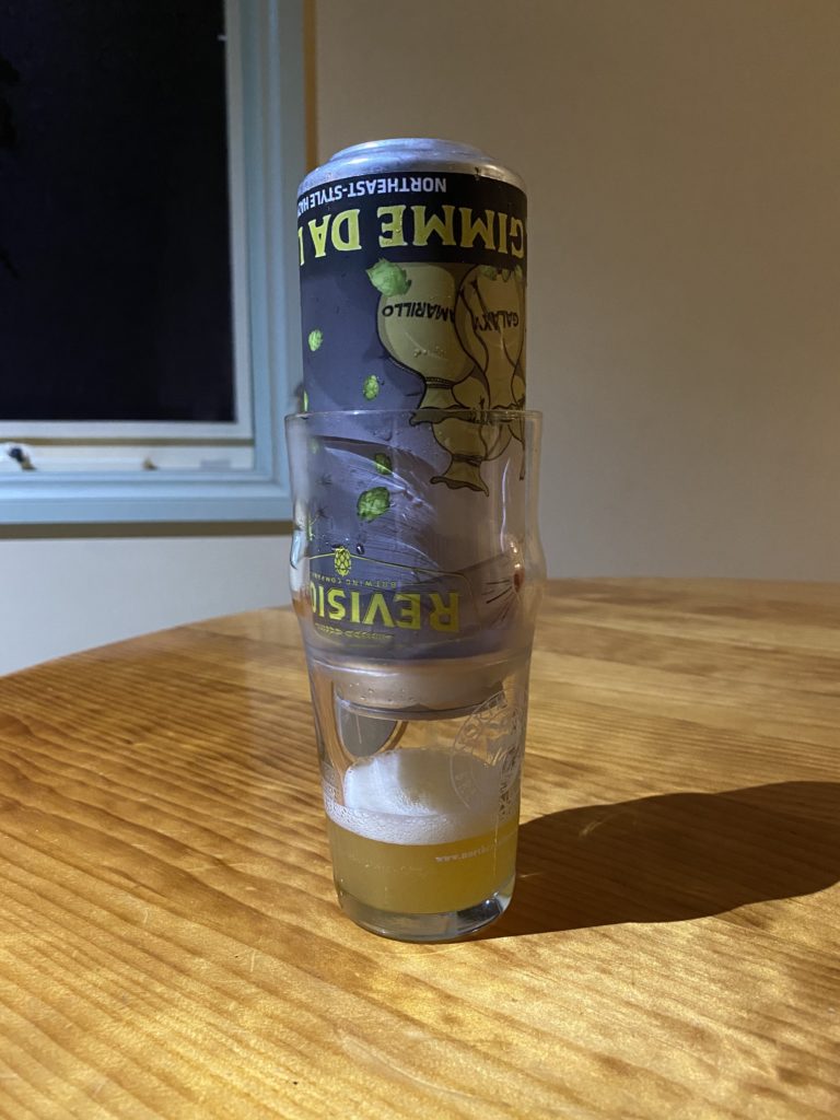 a beer can sits upside down inside a glass, draining very slowly